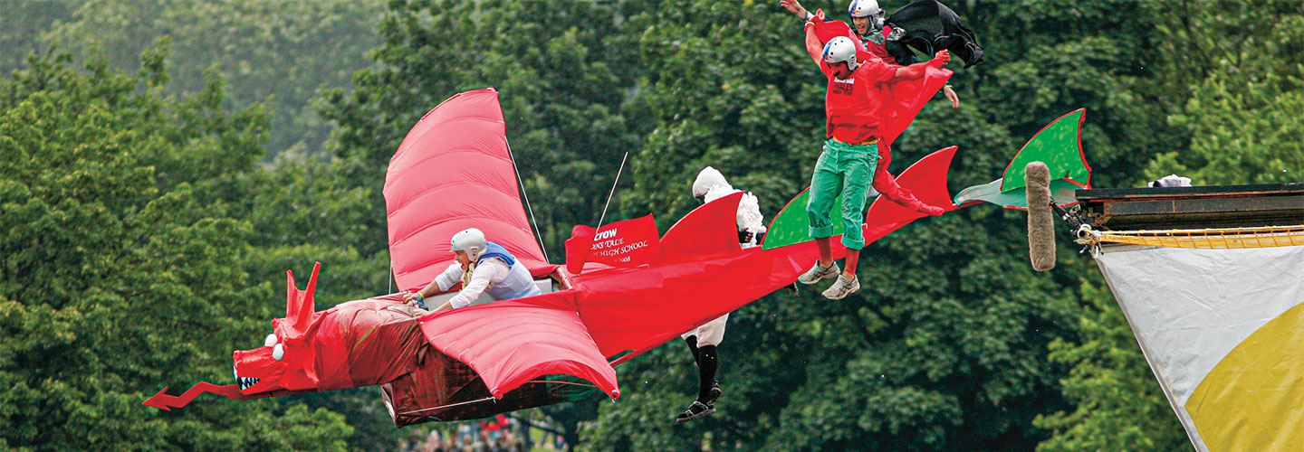 Photo of a person in a hand-made flying machine resembling a red dragon